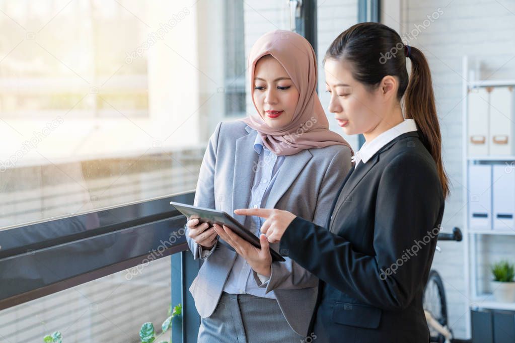 Two office lady looking at the tablet.