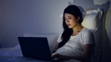 iş kadını sonrasında rahat yatak yatak odasında oturup bilgisayarla çalışma. karışık yarış Asya Çin yapımı.