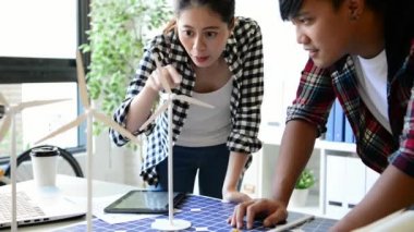 kadın alternatif enerji mühendisi bir yel değirmeni güç örnek model tutun ve stüdyoda alternatif güç kaynağı için onun erkek arkadaşı ile tartışmak