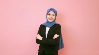 Kameraya bakarak ve takım elbise giyim ayakta pembe arka planda giyen kadın eller profesyonel emin Müslüman iş geçti.