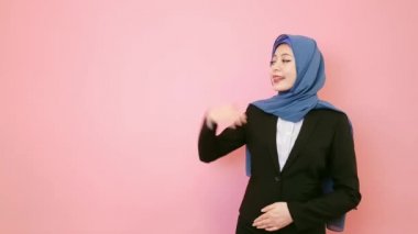 gülümseyen genç Müslüman office alt yüze kamera pembe duvar arka plan üzerinde izole jest başparmak ile sunan duruş yapma.