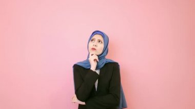 Genç Müslüman kadın şirket lider zorluk sorun duygu mutsuz ve pembe bir arka plan düşünme çözüm içinde ayakta karşılaştı.