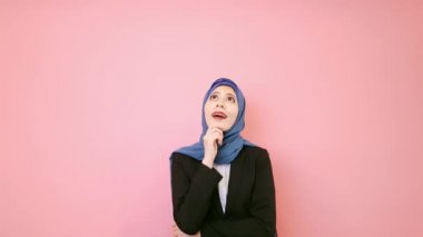 pembe arka planda duran ve kamera gülümseyen seyir çekici genç Müslüman kadın ofis işçi gösteren işaret fikir jest.