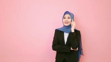 mutlu gülümseme başarılı Müslüman kadın Yöneticisi üzerinde pembe arka plan izole müşteri ile konuşurken telefon görüşmesi.