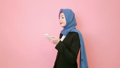 pembe arka plan izole müşteri ile konuşurken telefon üzerinde yürüyen mutlu gülümseme başarılı Müslüman kadın Yöneticisi.