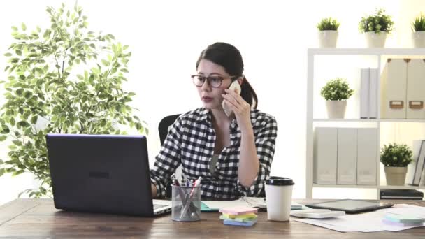 快乐有吸引力的女性商业工作者使用移动笔记本电脑在家工作 并通过手机电话寻找合作伙伴讨论计划的文件信息 — 图库视频影像