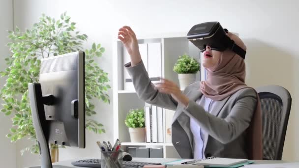 elegante attraktive muslimische Büroangestellte mit VR-Brille sitzt am Arbeitsplatz und benutzt Hände, die 3D-Simulation berühren, um den Arbeitsplan zu organisieren.