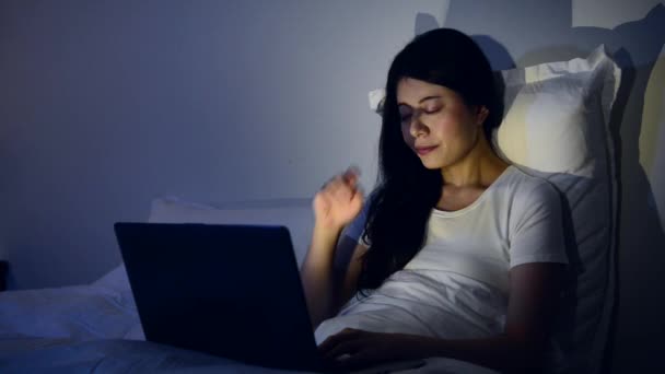 疲れたビジネスウーマン夜ノート パソコンで仕事をしてベッドのコンピューターに彼女の目をこすりながら 混血アジア中国モデル — ストック動画