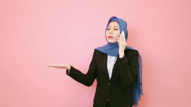 ピンクの背景に分離された顧客と話している電話でプロの美しいイスラム教徒の女性マネージャー — ストック動画