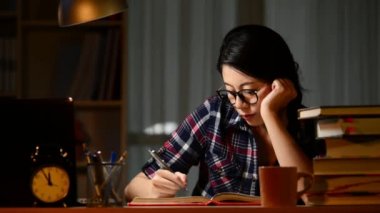 Geç saatlere kadar gece çalışmaları. Genç konsantre öğrenci hissediyorum uykulu lamba, karanlıkta onun odasına masasında yorgun. karışık yarış Asya Çin yapımı.