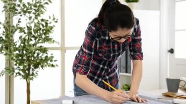 mutlu güzel Asyalı kadın ile onun müşteri yeni yapı büyük tasarım yaratıcı office Studio masasında iken onun iş için akıllı telefonda konuşurken mimar.