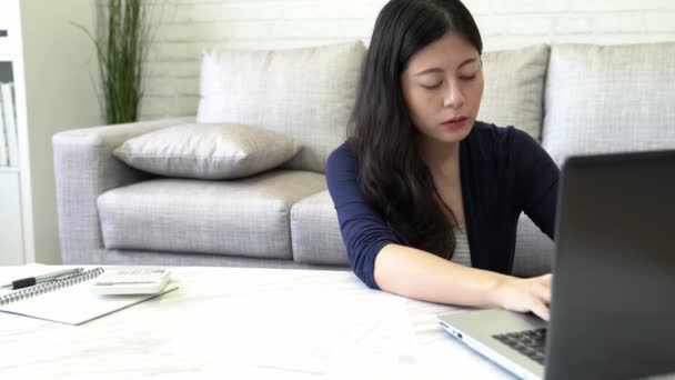 落ち込んで若いアジア女性使用手は 手形と自宅の居間でソファーに座っていた銀行の口座残高を確認した後彼女の顔をカバーします インテリアと国内の家事の概念 — ストック動画