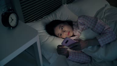 Yatakta yatıyordu ve manifatura smartphone üzerinde karanlık gecede kullanarak Modern Genç bayan. O kadar yalnız ve sosyal web sitesinde bulmak birisi ile sohbet etmek için çalışıyor.
