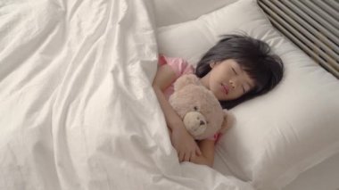 Asyalı güzel kız sessizce uyur ve tutarak onun şirin tüylü teddy ayı.