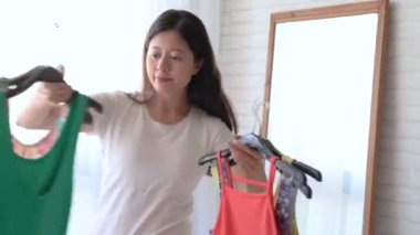 Hangi giysi giymek için modern bir genç Asyalı kadın hızlı hızlı hareket alır.