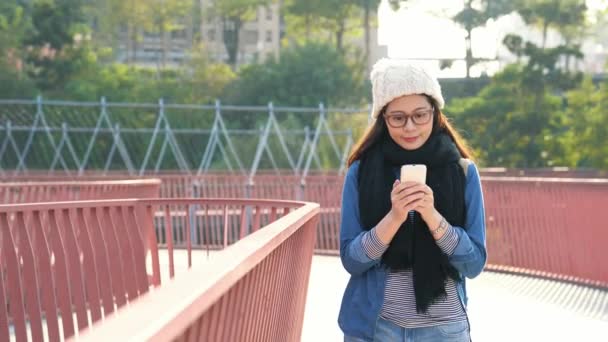 Jovem Mulher Asiática Mensagem Texto Usando Smartphone Andando Ponte Urbana — Vídeo de Stock