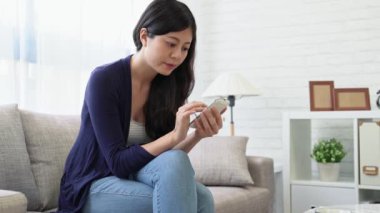 Evdeki gülümseyen genç kadın kanepede dinlenirken, akıllı telefon ve mesajlaşma, teknoloji ve iletişim konsepti kullanıyor..