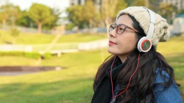 smartphone müzik Şehir Parkı üzerinde şık Sevimli Asya kadın hoşlanır, kız kış sezonu güneşli bir günde hoşlanır.