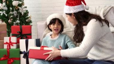 sonra o aldı ve Noel hediye kutusu açık--dan annesi evde koltukta oturan küçük şirin Asyalı kız sürpriz yüz ifadesi hissediyor.