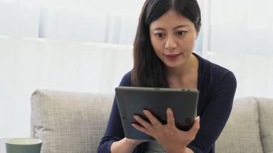 pencere görünümü dışında bakarak ve tatil zaman zevk ya da evde telefon defteri bilgisayar ile çalışma kanepede oturan Kupası kupa tutan çekici kadın.