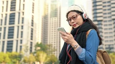 güneşli bir günde Şehir Parkı içinde hareket eden smartphone kullanarak rahat kıyafet öğrenci.
