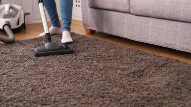 Günlük temiz, ev ve ev kavramı sırasında evde halı temizlerken elektrik süpürgesi kullanan genç kadın kadeh kaydırmak.