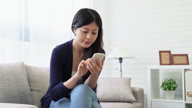 Güzellik erkek gülümseyen dolly çekim model pencere rahat kanepe önünde oturan ve online haber tarama hareket eden smartphone seyir ve evde pencerenin dışındaki güzellik manzarasının tadını çıkarın.