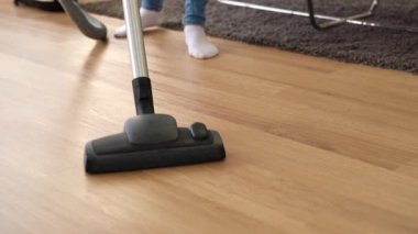 Dolly bahar temiz sırasında oturma odasında elektrikli süpürge ile ahşap zemin temizliği ev hanımı bir kadeh. Ev kavramı.