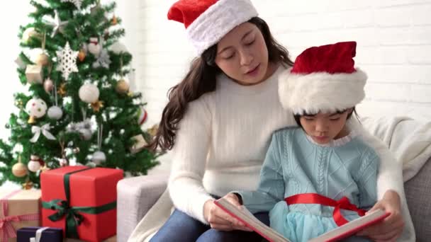 Pretty Young Asian Mom Reading Book Her Cute Daughter Christmas — Stock Video