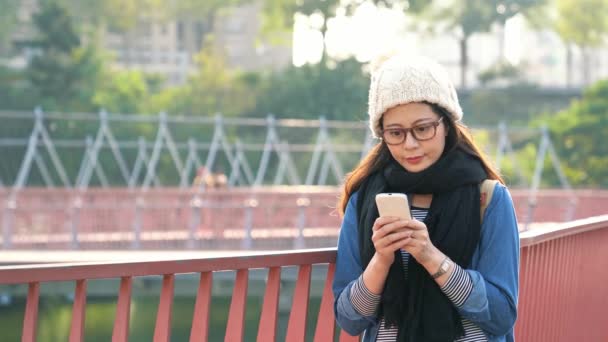 年轻妇女使用智能手机在城市桥梁室外 女孩在手机上浏览互联网并思考 — 图库视频影像