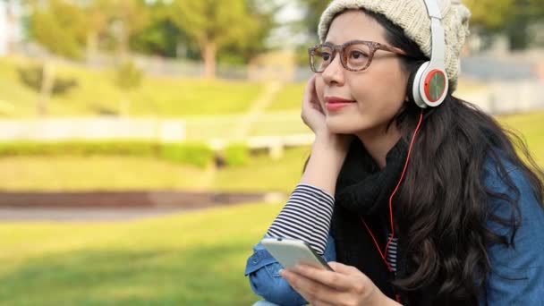 Asia Girl Student Enjoys Listening Music Smartphone Park Sitting Grass — Stock Video