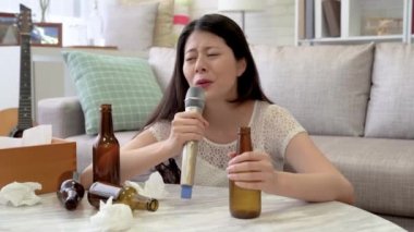 Asyalı dertli kadın şarkı karaoke onun oturma odasında. O bağırdı ve kalbi acıyla serbest bırakmak için bağırdı.