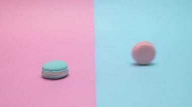 İki macarons punchy pastel zemin üzerine yerleştirerek. Etrafında mavi bir haddeleme ve sonra durdu pembe bir.