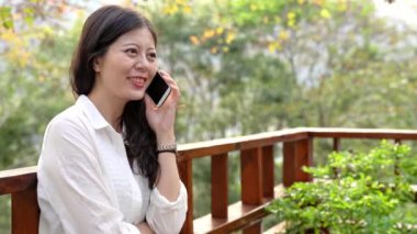 Akıllı telefon sonbahar Asyalı kadın sonbaharda cep telefonu üzerinde konuşurken. güneş patlaması yeşillik içinde Smartphone konuşmayı kız.