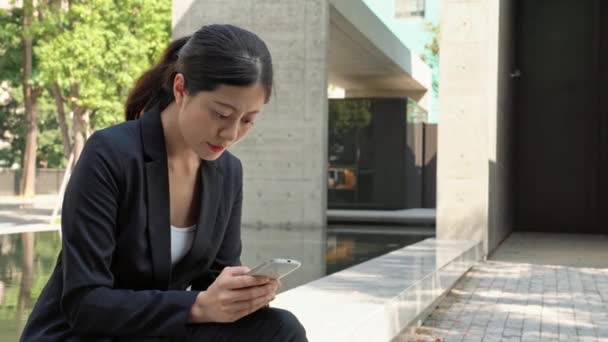 美丽的企业妇女坐在外面高兴与好消息通过移动电话在现代城市 — 图库视频影像