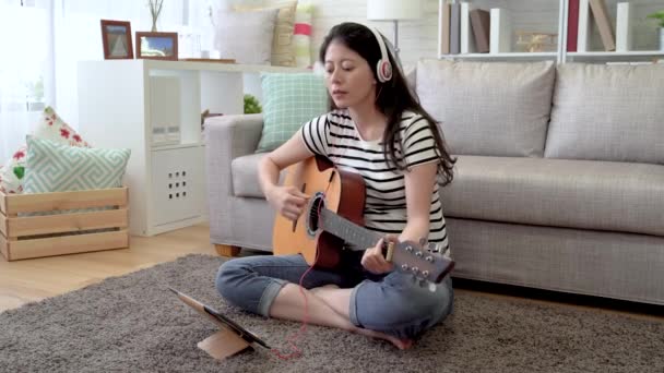 ビートを正確にカウントするアジアの女性タップとうなずくとデジタル タブレットを使用して オンライン ギターの学習自己の素早い動き — ストック動画