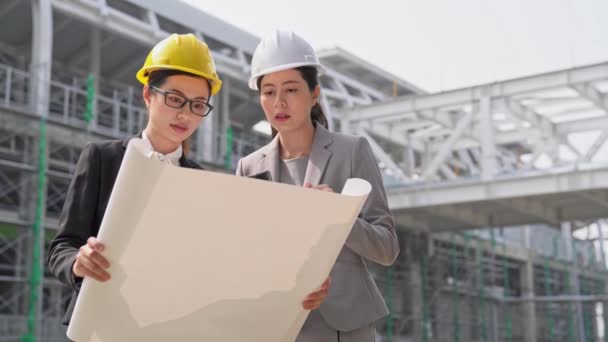 工事現場や高層ビルの建築現場での建築家とアジアの建設 女性エンジニア ディスカッション — ストック動画