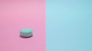 Macaron masaya yuvarlandı ve maviyi durdu. Punchy pastel arka plan üzerinde.