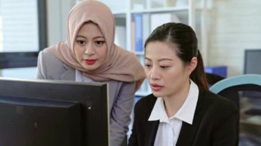 Ofiste bir masada oturan bir proje ile birlikte bilgisayar üzerinde iki güzel iş kadınları