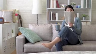 Asya modern kadın ele geçirmek bazı yabancı gazete okumak ve oturma odasında sıcak çay içmek için kısa bir mola zaman.