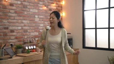 Kişisel konserini mutfakta tutan kadın ağır çekim. O-miş gibi Kepçe mikrofon.