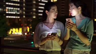 sohbet ofis dışında toplantı ve cep telefonu kullanarak iki kız meslektaşım var birlikte şehir sokak işten sonra.