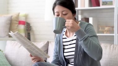 Asyalı kadın sonunda o oturma odası gazetede okuduktan sonra yabancı ülkede neler olduğunu dışarı rakamlar. O da aynı anda bir fincan sıcak çay vardır.