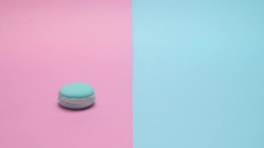 Macaron masaya yuvarlandı ve maviyi durdu. Punchy pastel arka plan üzerinde.
