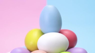 Punchy pastel arka plan üzerinde dönen ve bir yığın halinde yığılmış renkli yumurta.