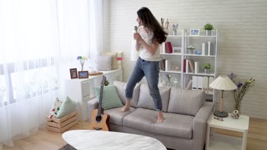 Mikrofonu tutan ve dans ve evde oturma odasında sallanan Asyalı kadın. Bir hızlı hareket.