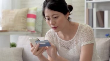 Bir şey online satın almak için kredi kartı şifresini tuşlayarak Asyalı bir kadın. Oturma odasında kolayca ve uygun online alışveriş tamamlandıktan.