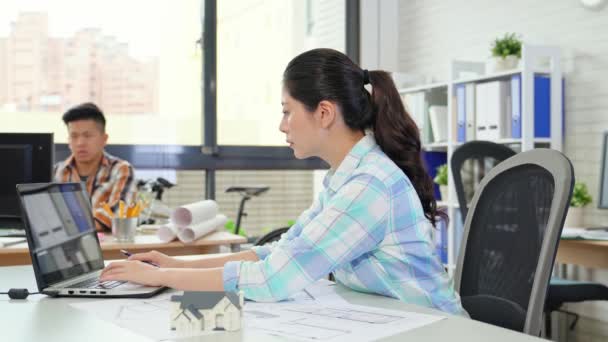 Mujer Arquitecto Trabajando Computadora Mientras Compañero Trabajo Trabajando Fondo Luego — Vídeo de stock