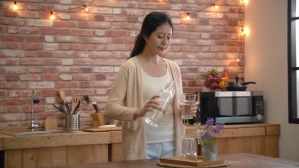 アジアの女性のグラスに水を注ぐのスローモーションし それを飲んだ — ストック動画