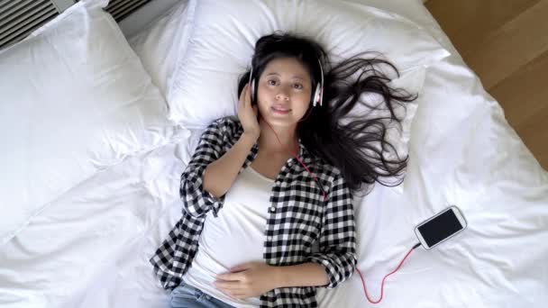 亚洲女人沉迷于悦耳的音乐 通过手机和耳机 噪音不再困扰她 在高角度视图上 — 图库视频影像